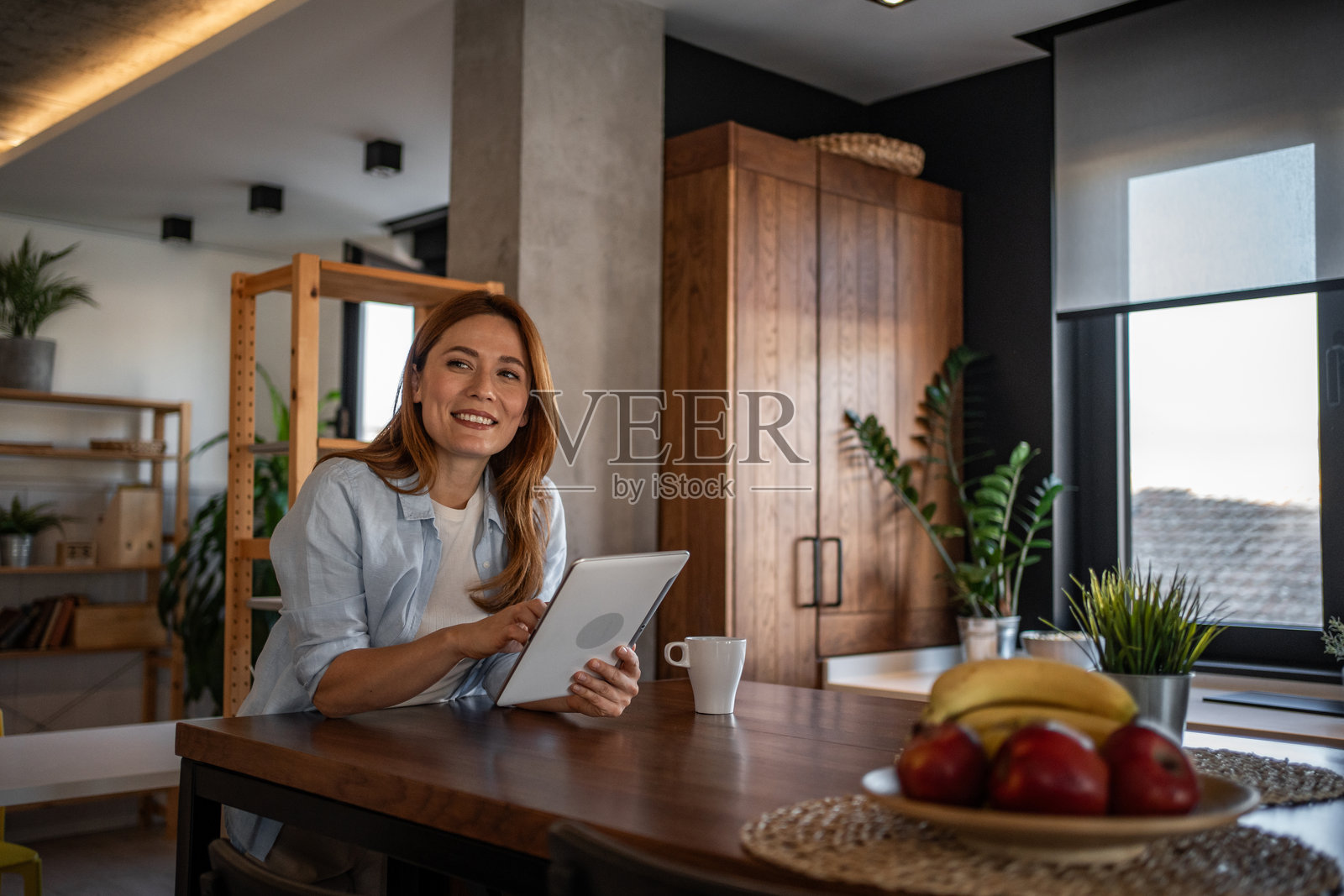 微笑的女性在现代厨房中使用平板电脑照片摄影图片