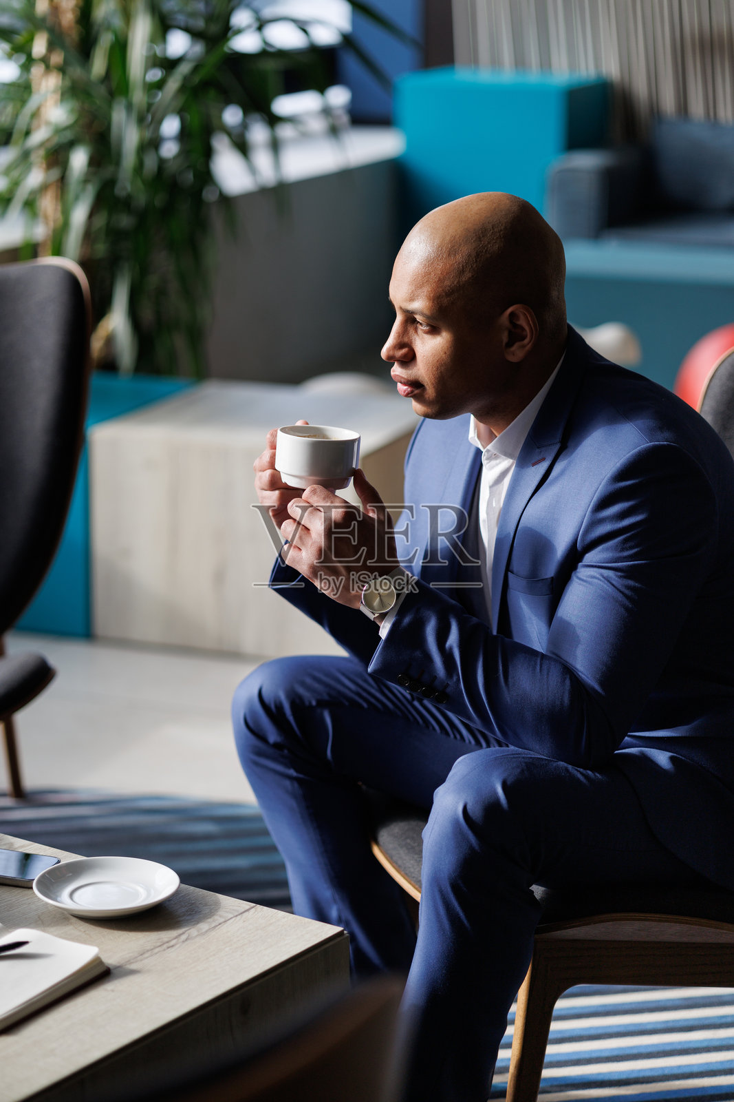 非裔美国商人在现代酒店大堂里拿着咖啡照片摄影图片