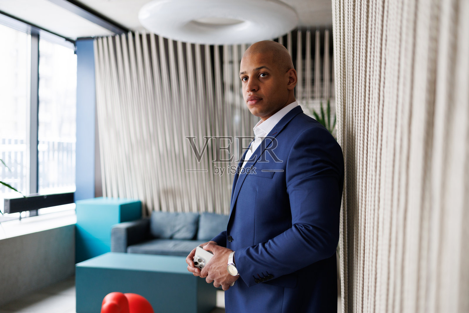 身穿西装的非裔美国商人在现代酒店中拿着智能手机照片摄影图片