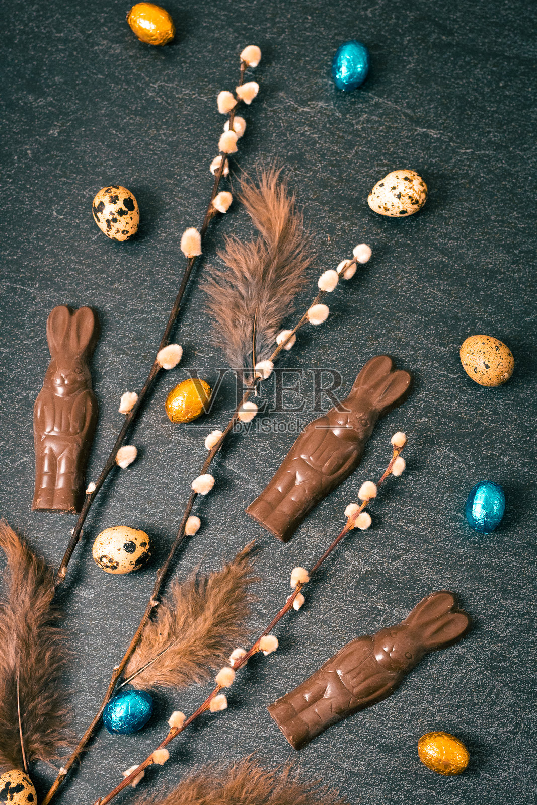 黑色背景上的巧克力兔子、柳树枝和复活节彩蛋。照片摄影图片