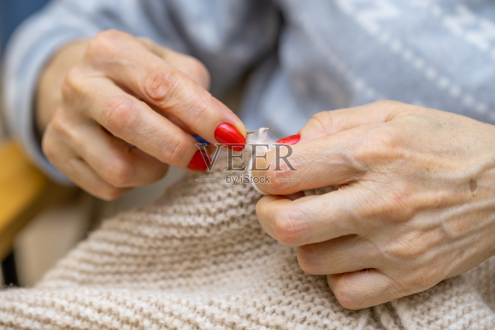 一位无法辨认的女性正在用粗针编织手工衣物，手部特写，使用羊毛纱线。休闲活动的概念。用纱线在粗针上编织。照片摄影图片