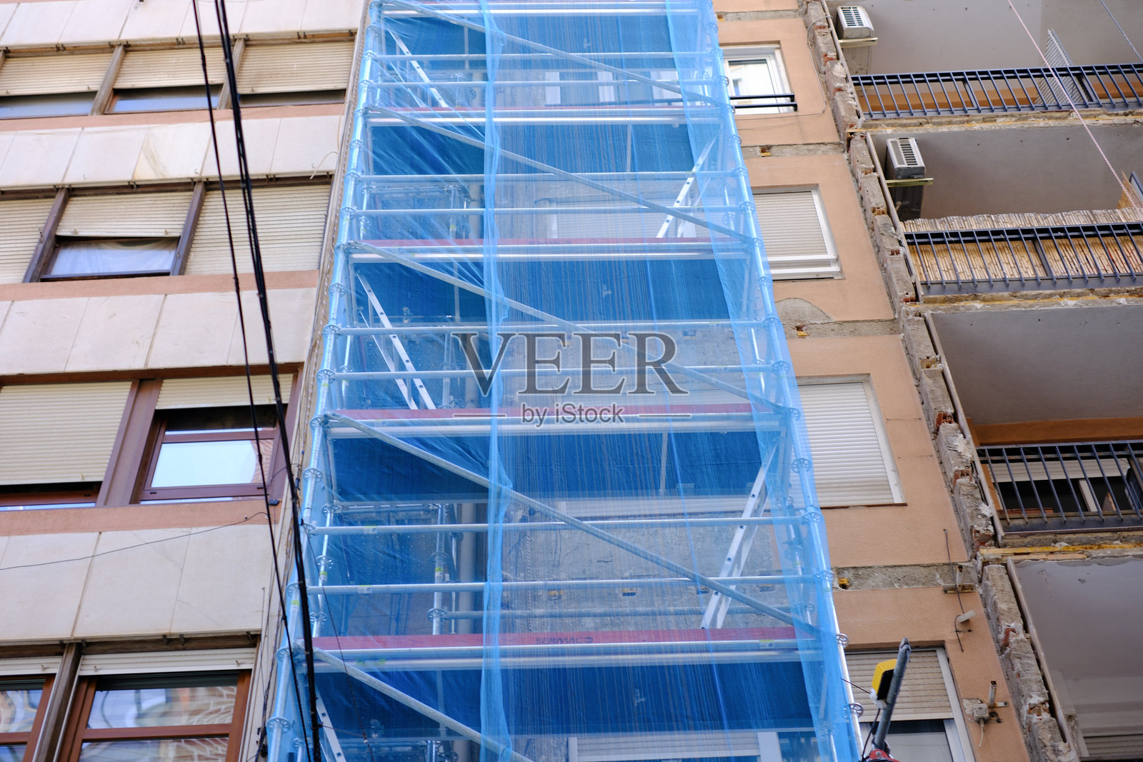 城市建筑翻新，搭建了脚手架和蓝色保护网。照片摄影图片