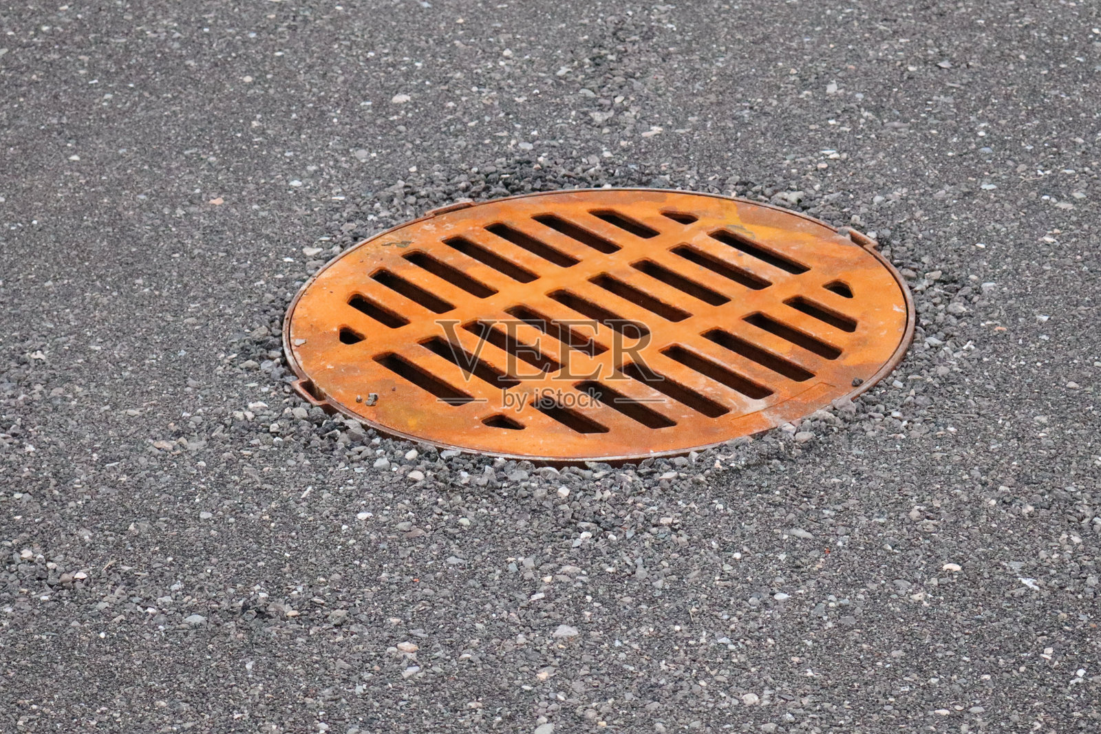 新铺沥青上的橙色金属雨水篦子照片摄影图片