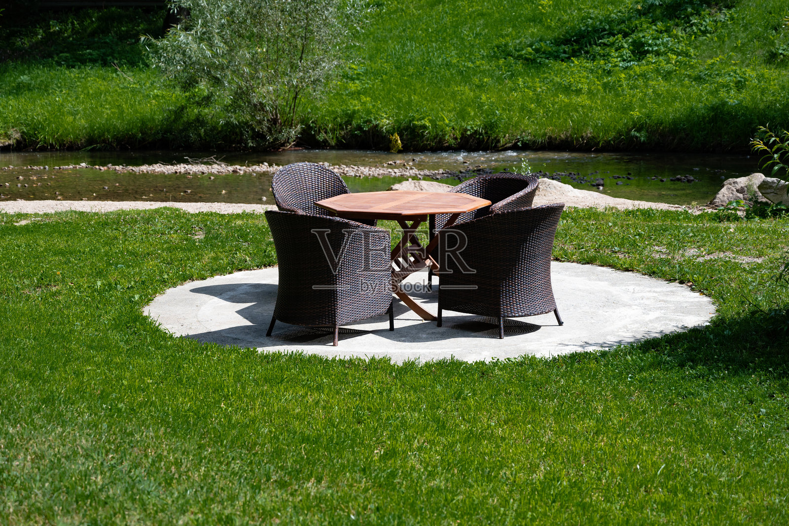 户外休息区，配有藤制和金属家具，坐落在郁郁葱葱的草坪上。照片摄影图片