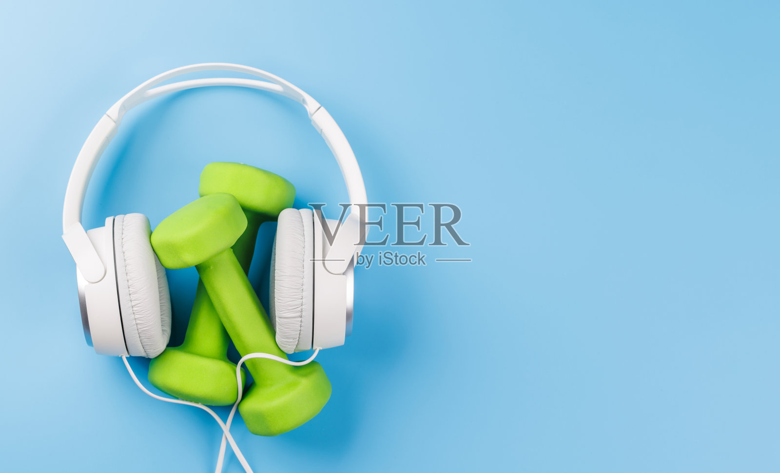 平铺的耳机和哑铃，背景为明亮的蓝色照片摄影图片