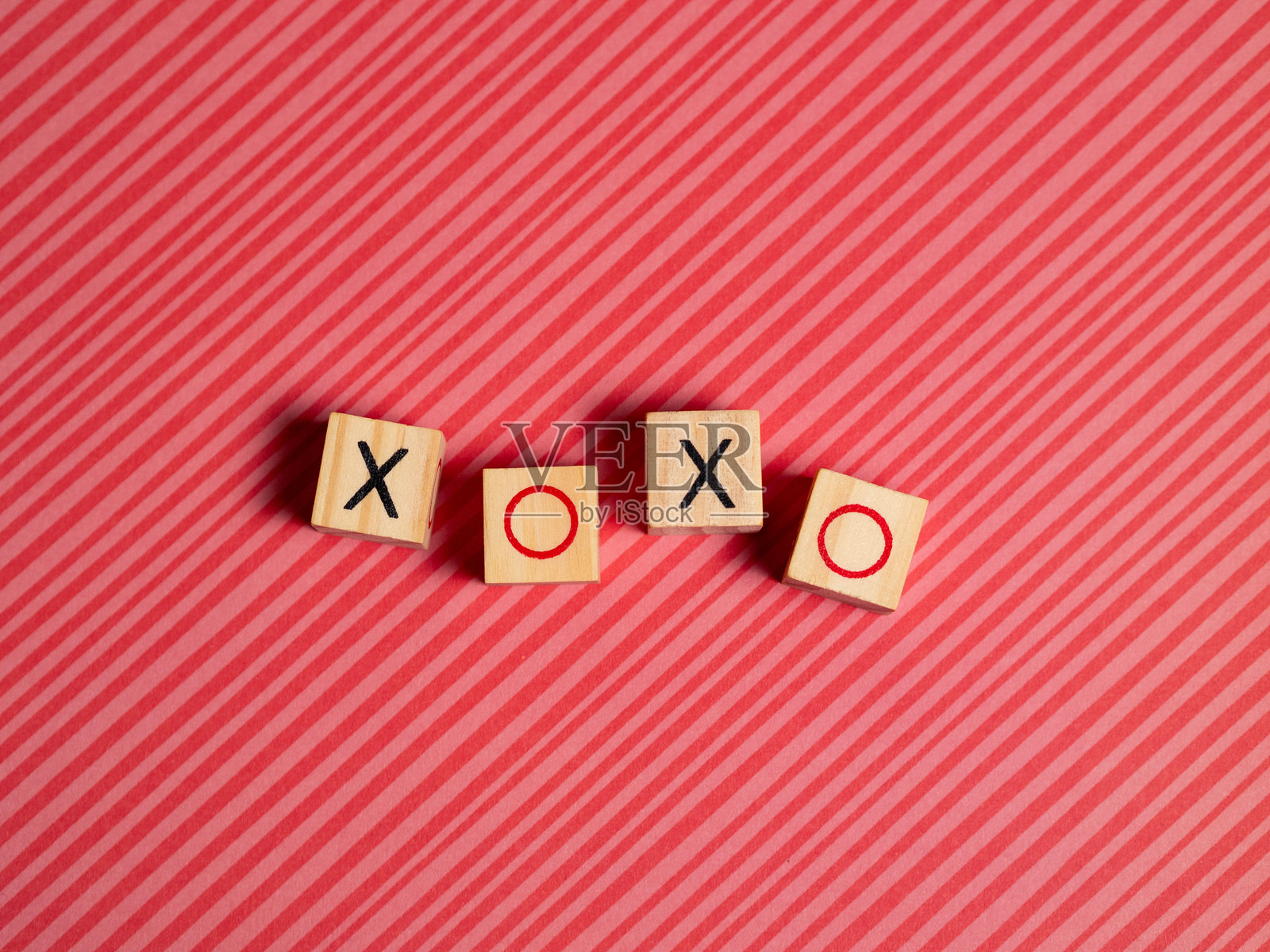 游戏棋子拼写的XOXO以俏皮的图案排列在多彩的背景上照片摄影图片