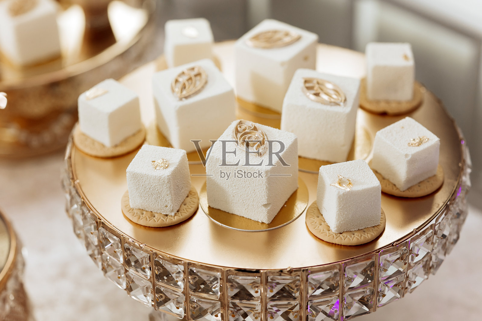 一盘白色和金色的甜点放在一个镀金的支架上照片摄影图片