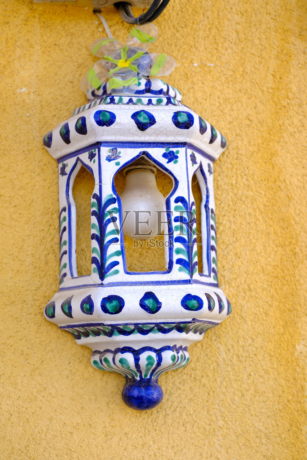 传统摩洛哥灯笼，蓝色图案映衬在黄色墙壁背景上照片摄影图片