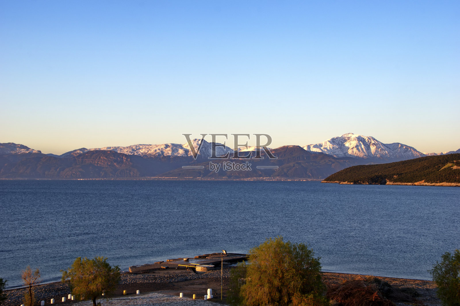 日出时分，海滩和大海的景色，背景是雪山。照片摄影图片