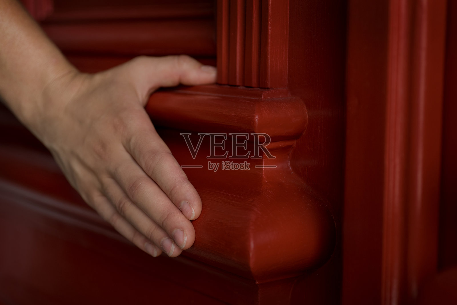修复门的特写，带有雕刻装饰、倒角和一只女性手的触碰。照片摄影图片