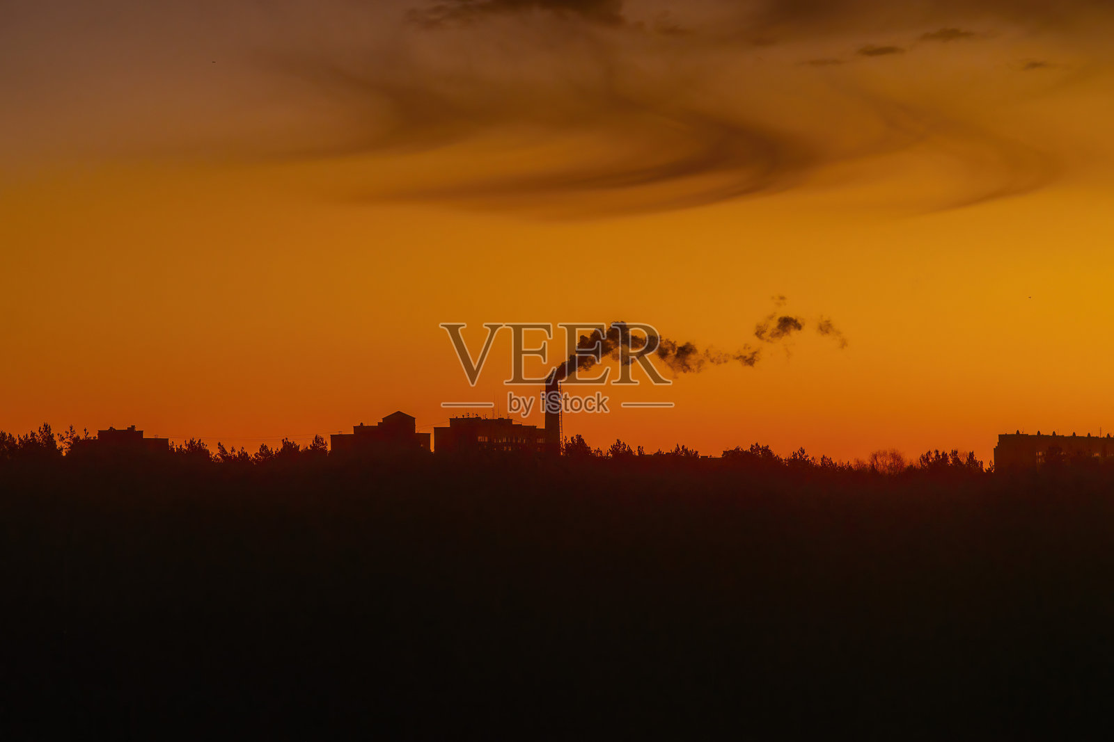 工厂烟囱的剪影，黑色烟雾在日落时分的橙色天空中。背景留有空白空间，适合关于生态、污染和有害排放的主题文字。照片摄影图片