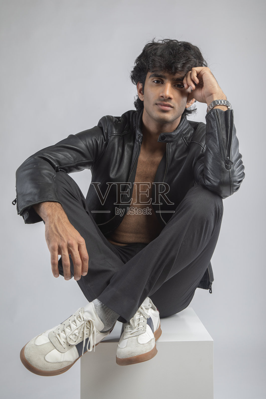 穿着夹克和运动鞋的男人坐在白色背景上照片摄影图片