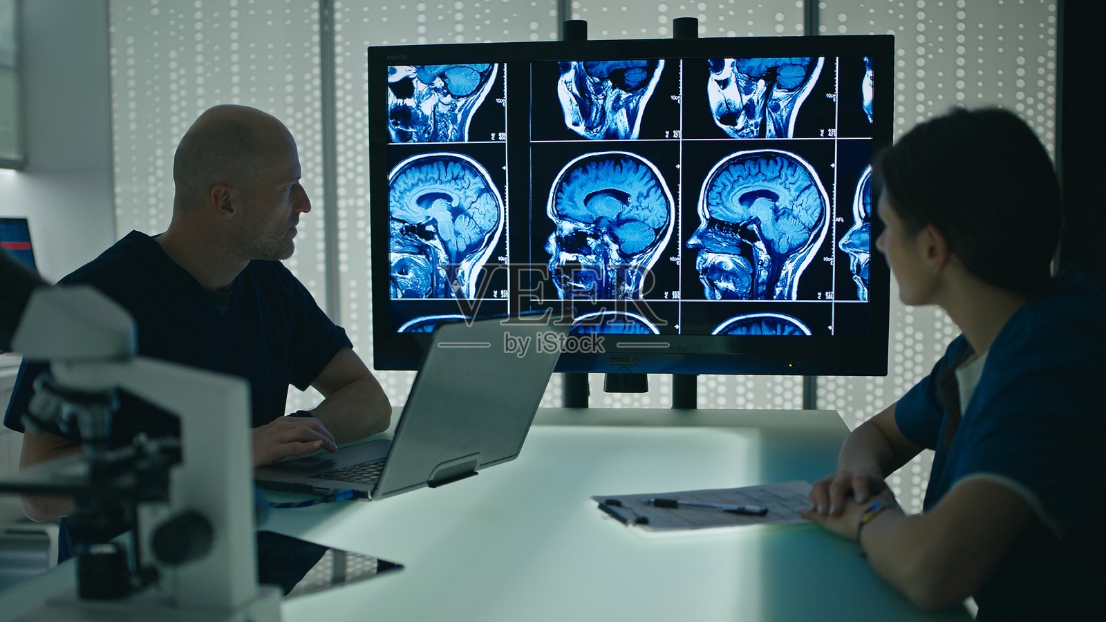 医生与另一位医生讨论磁共振成像（MRI）扫描。照片摄影图片