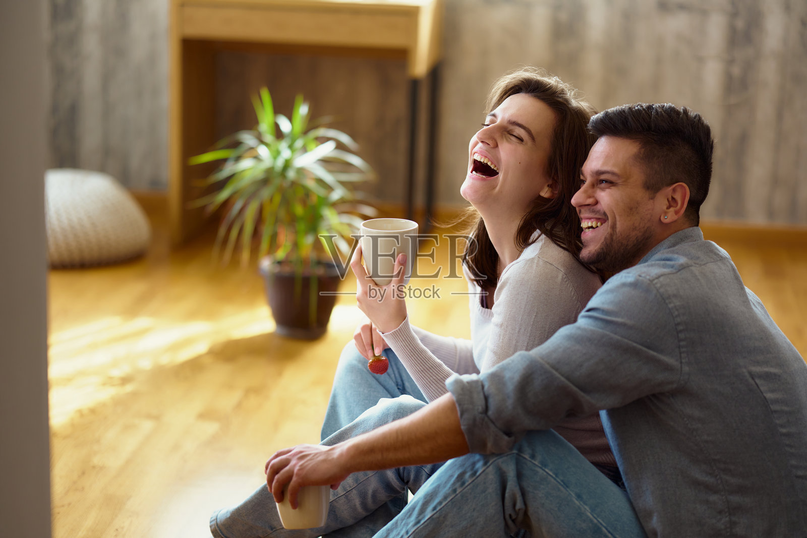 年轻情侣坐在家里的地板上喝咖啡照片摄影图片
