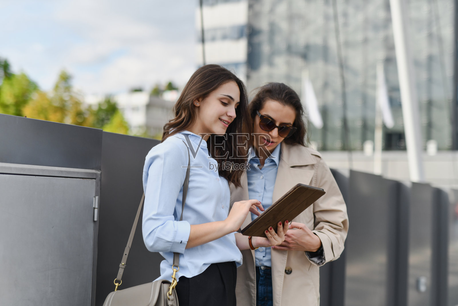 美丽的女性向好奇的朋友展示平板上的数字草图照片摄影图片