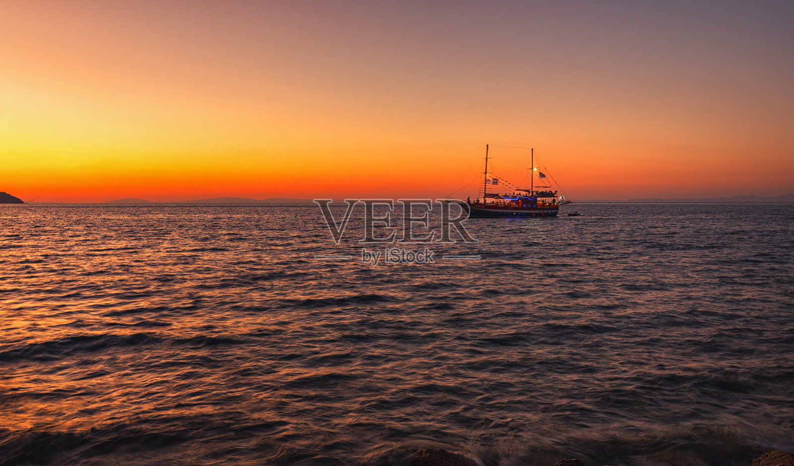 希腊岛屿上美丽日落下的游船照片摄影图片