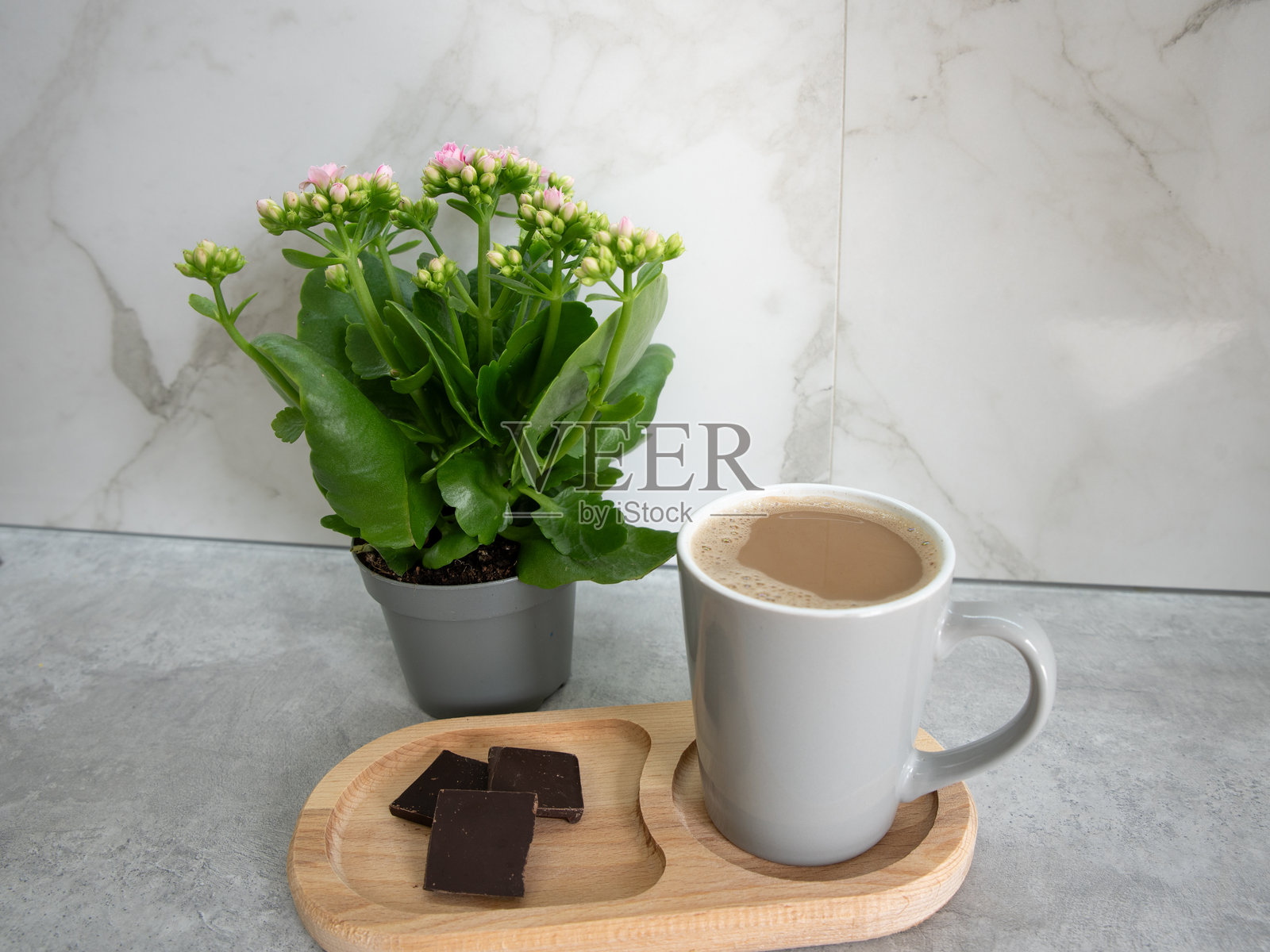 一杯咖啡和一块黑巧克力放在绿色花朵旁边。早晨日常。照片摄影图片