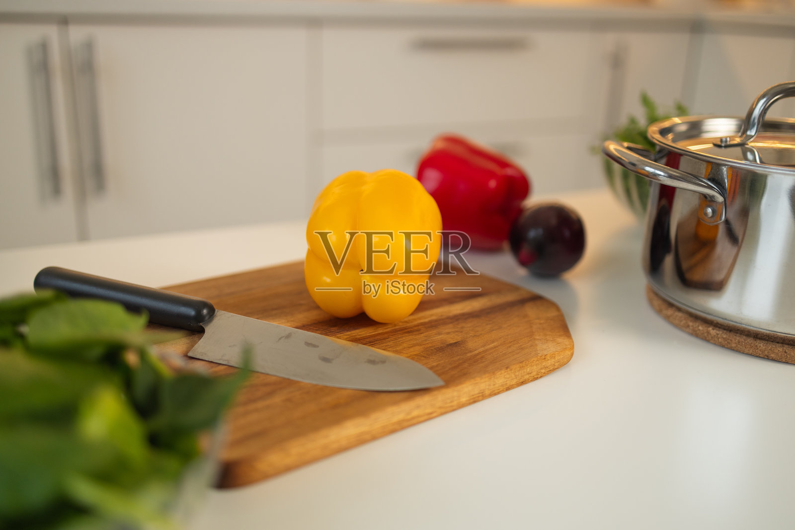 厨房里的木砧板上放着一只黄色甜椒和一把刀。照片摄影图片