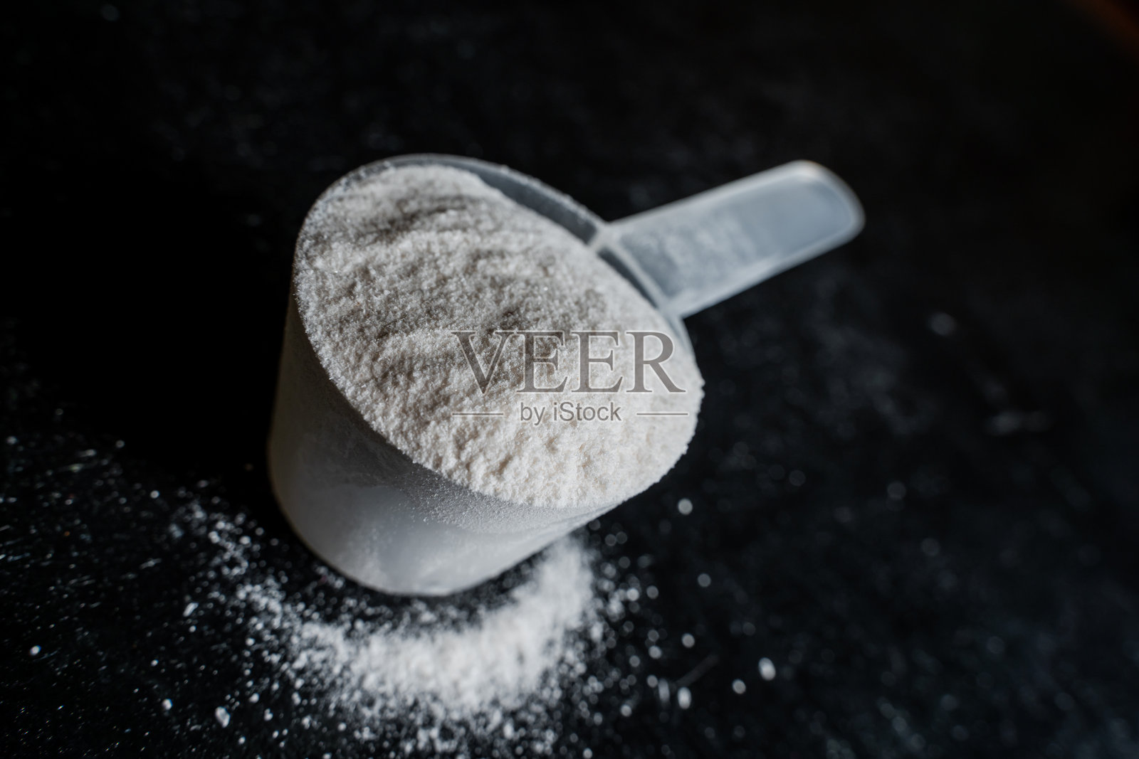黑色板上白色运动营养粉的勺子特写照片摄影图片