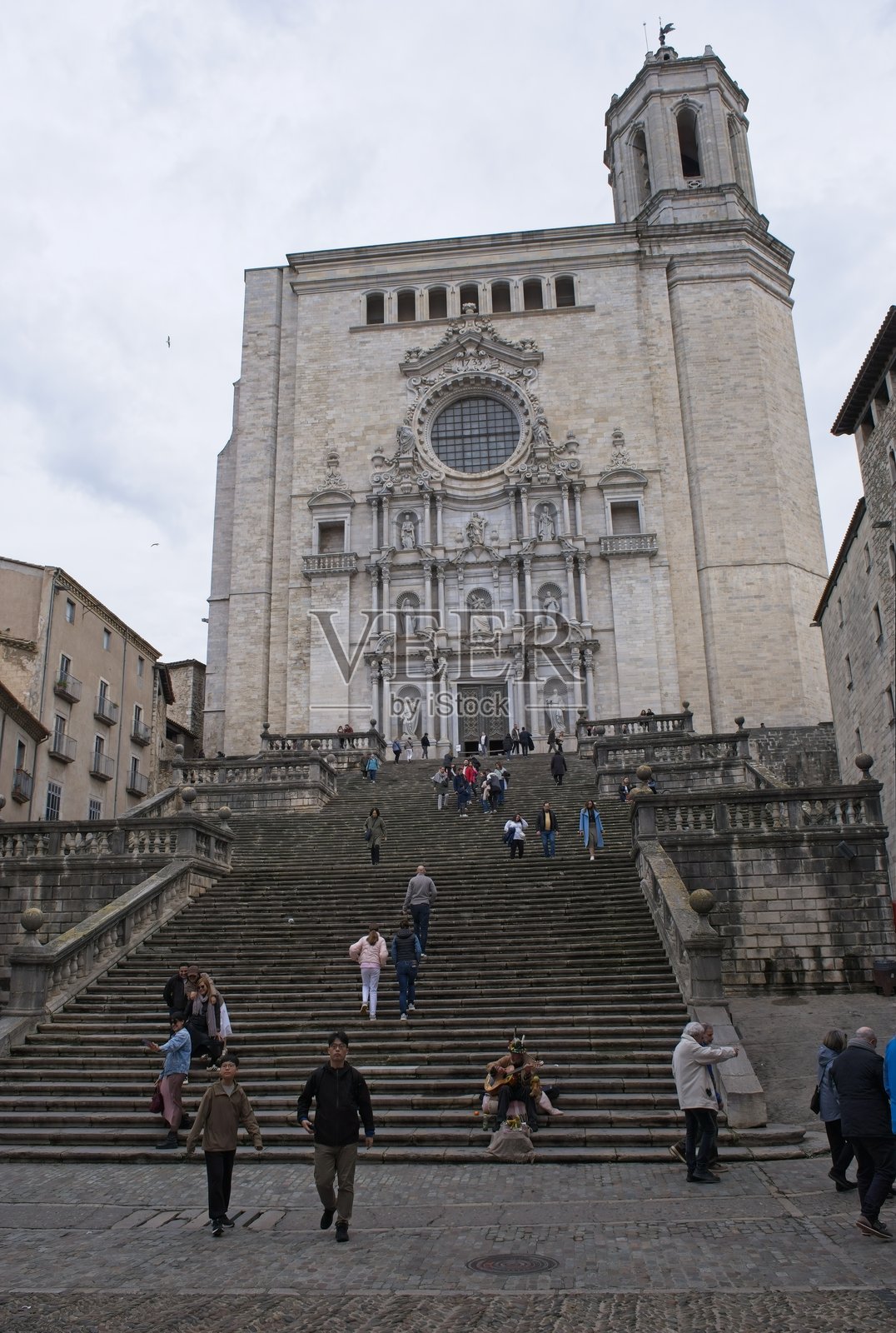 赫罗纳圣费利乌大教堂。人们在赫罗纳走动。街道，建筑。城市区域的生活方式。阴云密布的冬日。选择性焦点。照片摄影图片