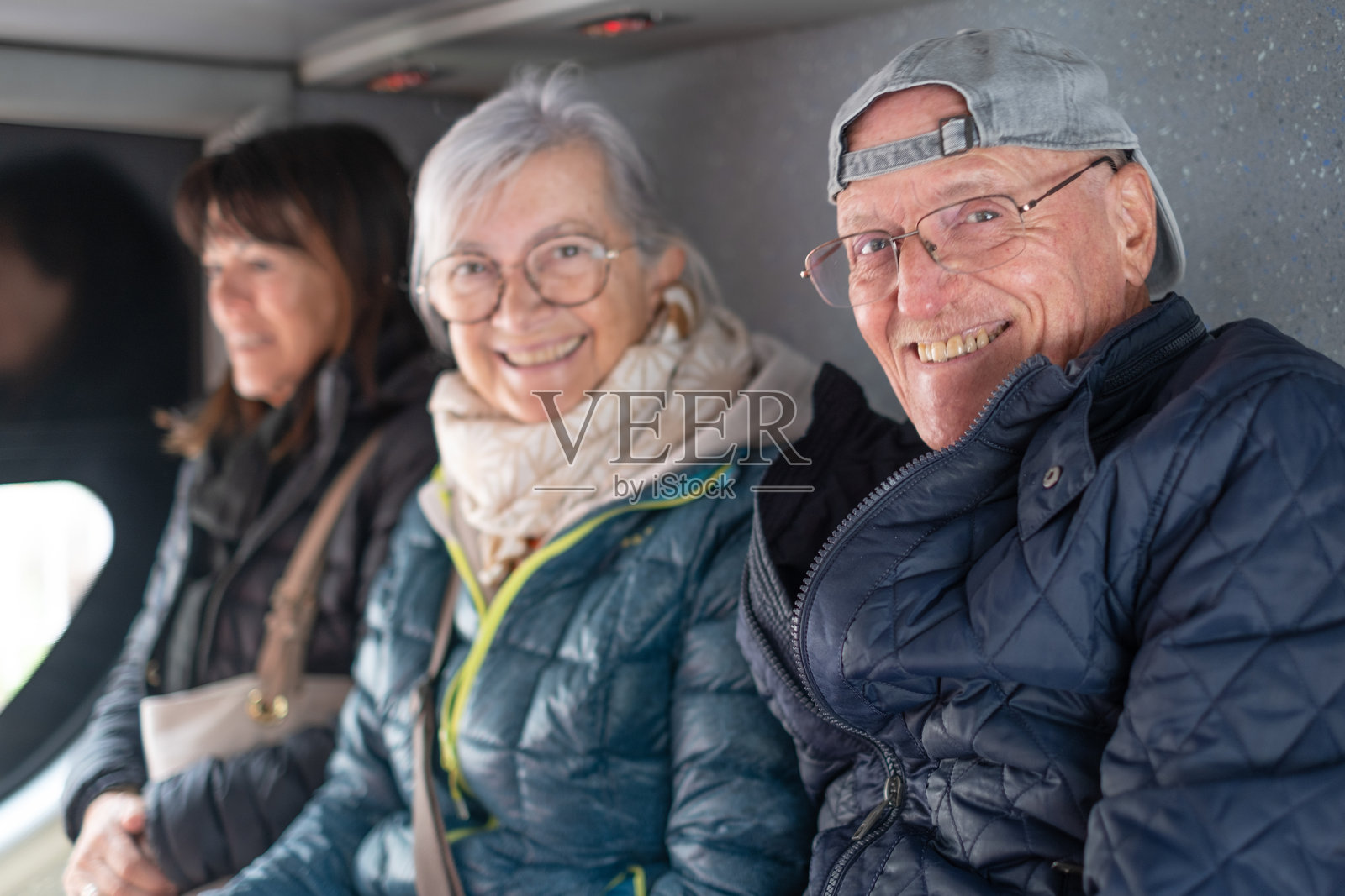 一群老年朋友在巴士上进行观光游，面带微笑地看着镜头。照片摄影图片