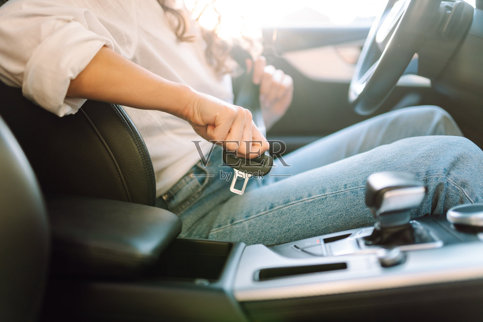 女性在驾驶座上系好安全带，以确保安全驾驶。照片摄影图片