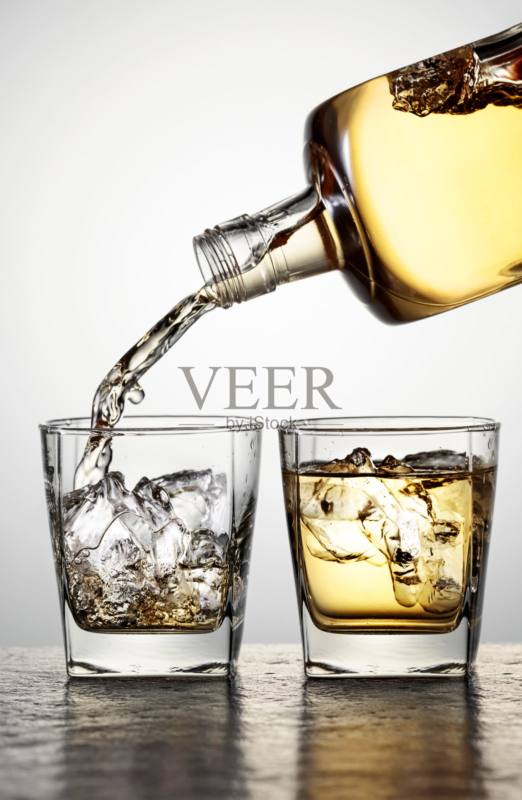 威士忌倒入装有冰块的酒杯中。照片摄影图片