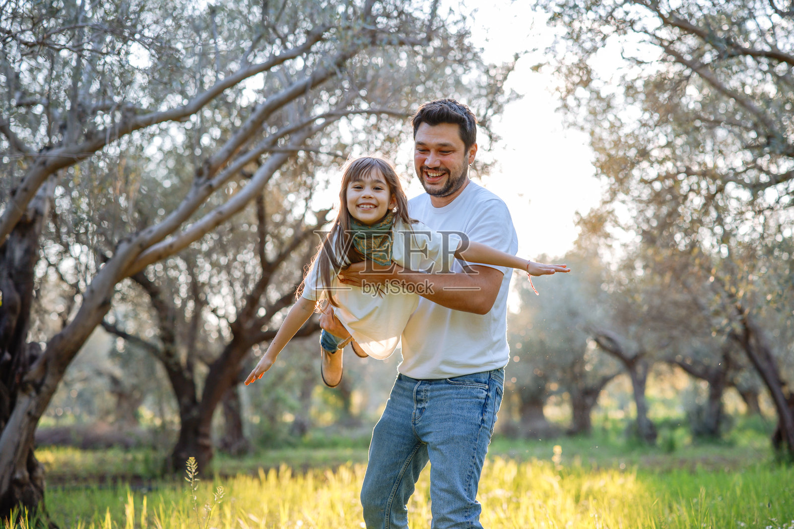 无忧无虑的年轻父亲和女儿在春天的日子里拥抱。照片摄影图片