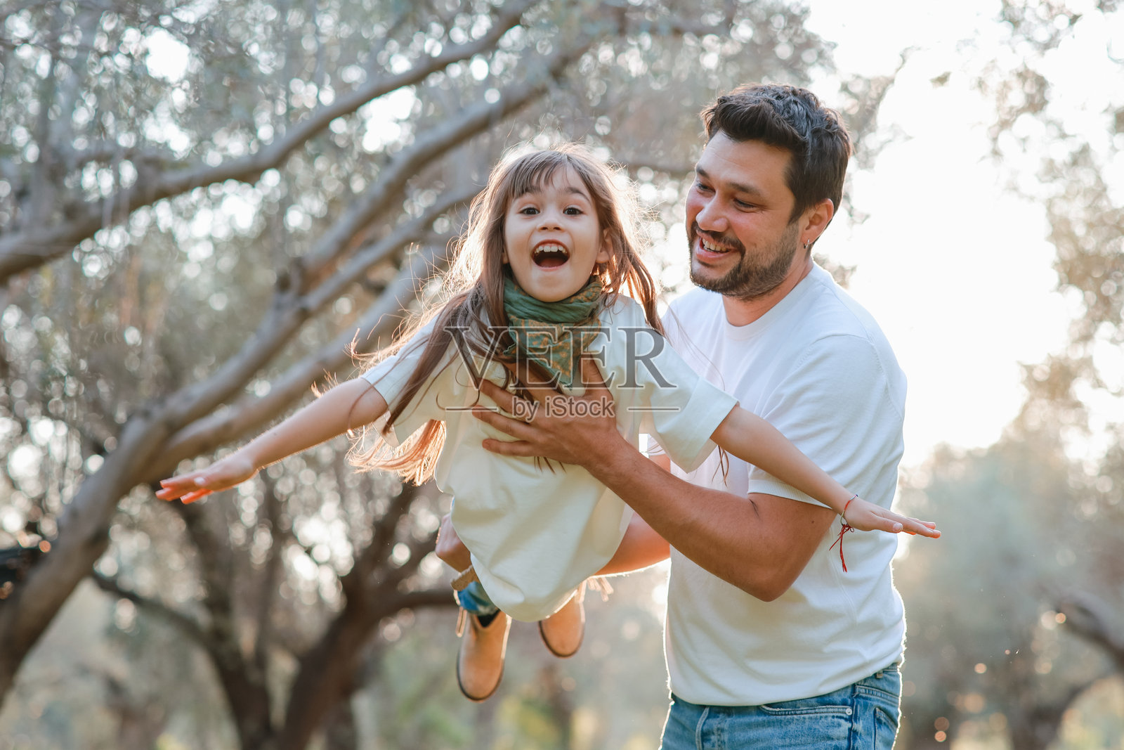 无忧无虑的年轻父亲和女儿在春天的日子里拥抱。照片摄影图片