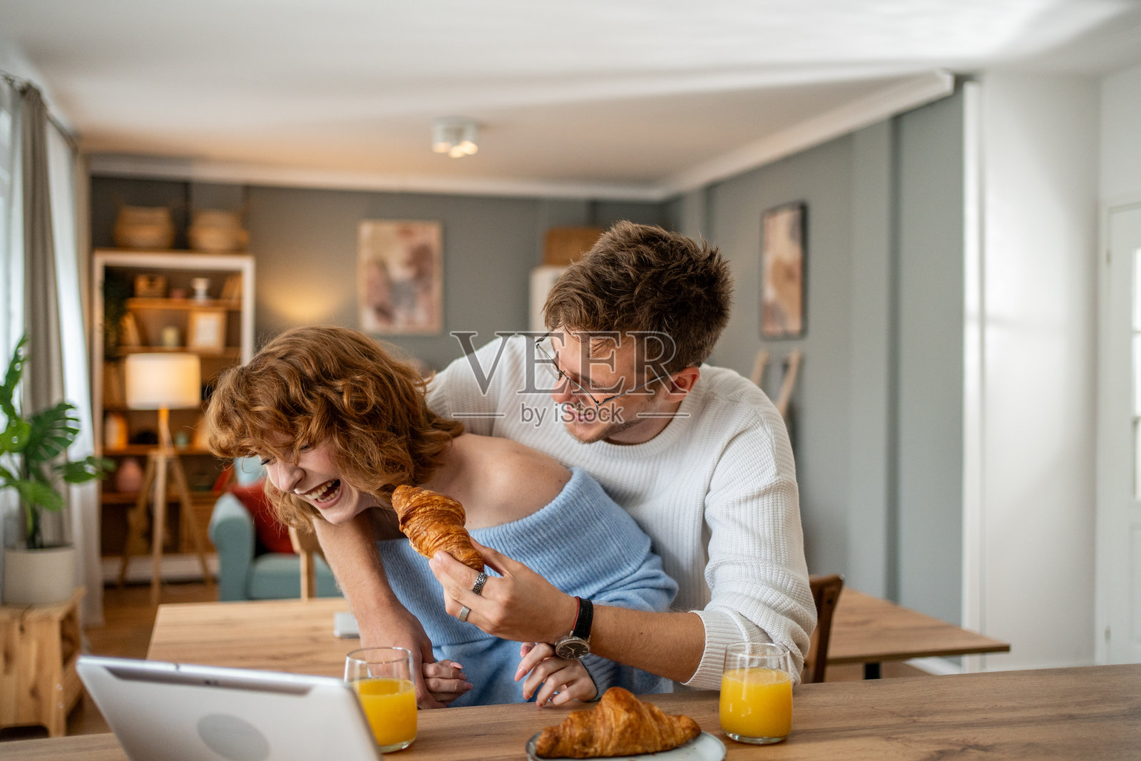 一对顽皮的情侣在吃早餐时玩得开心，同时在笔记本电脑上浏览互联网照片摄影图片