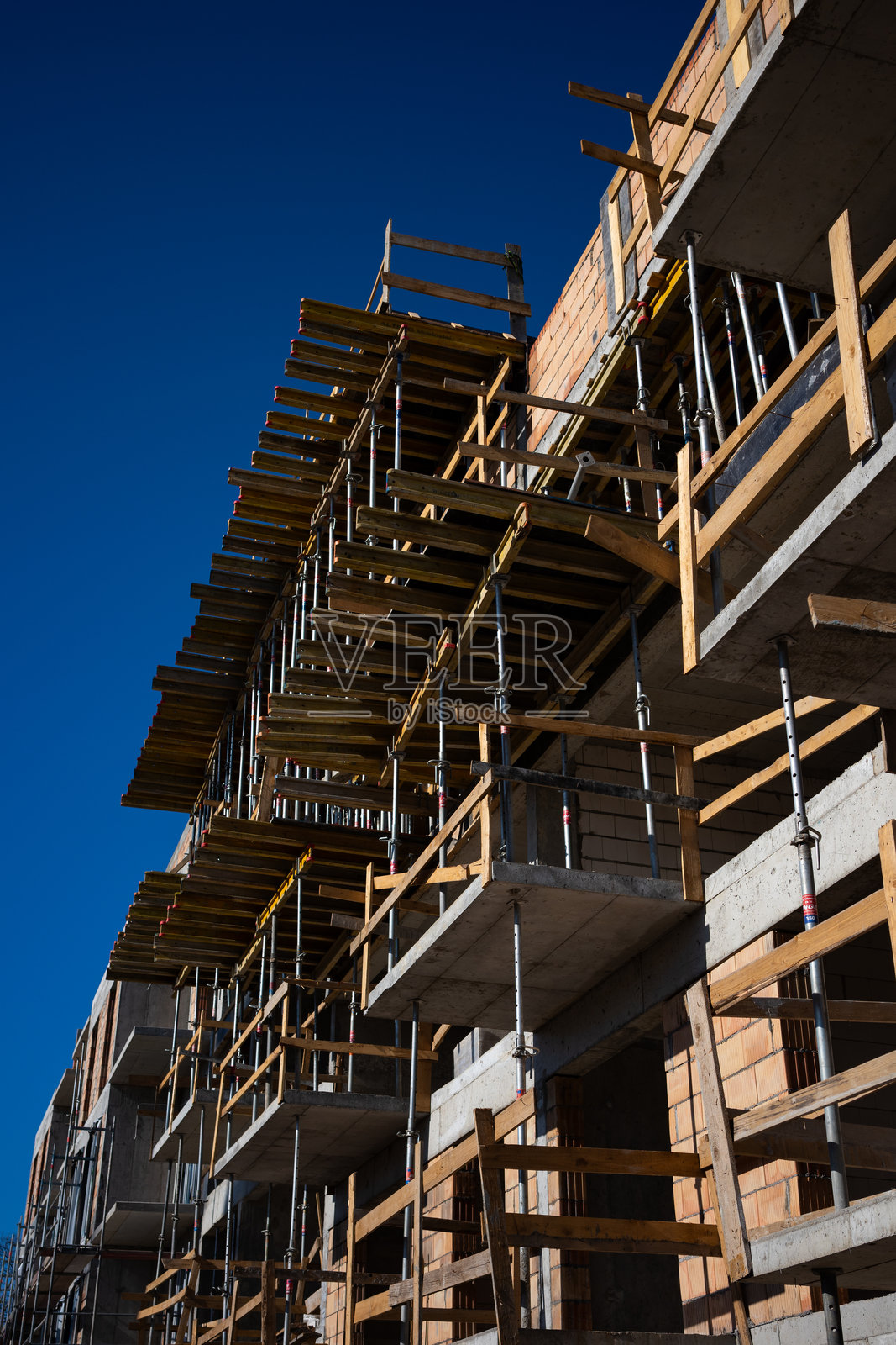 新建红砖公寓楼上的钢脚手架。照片摄影图片