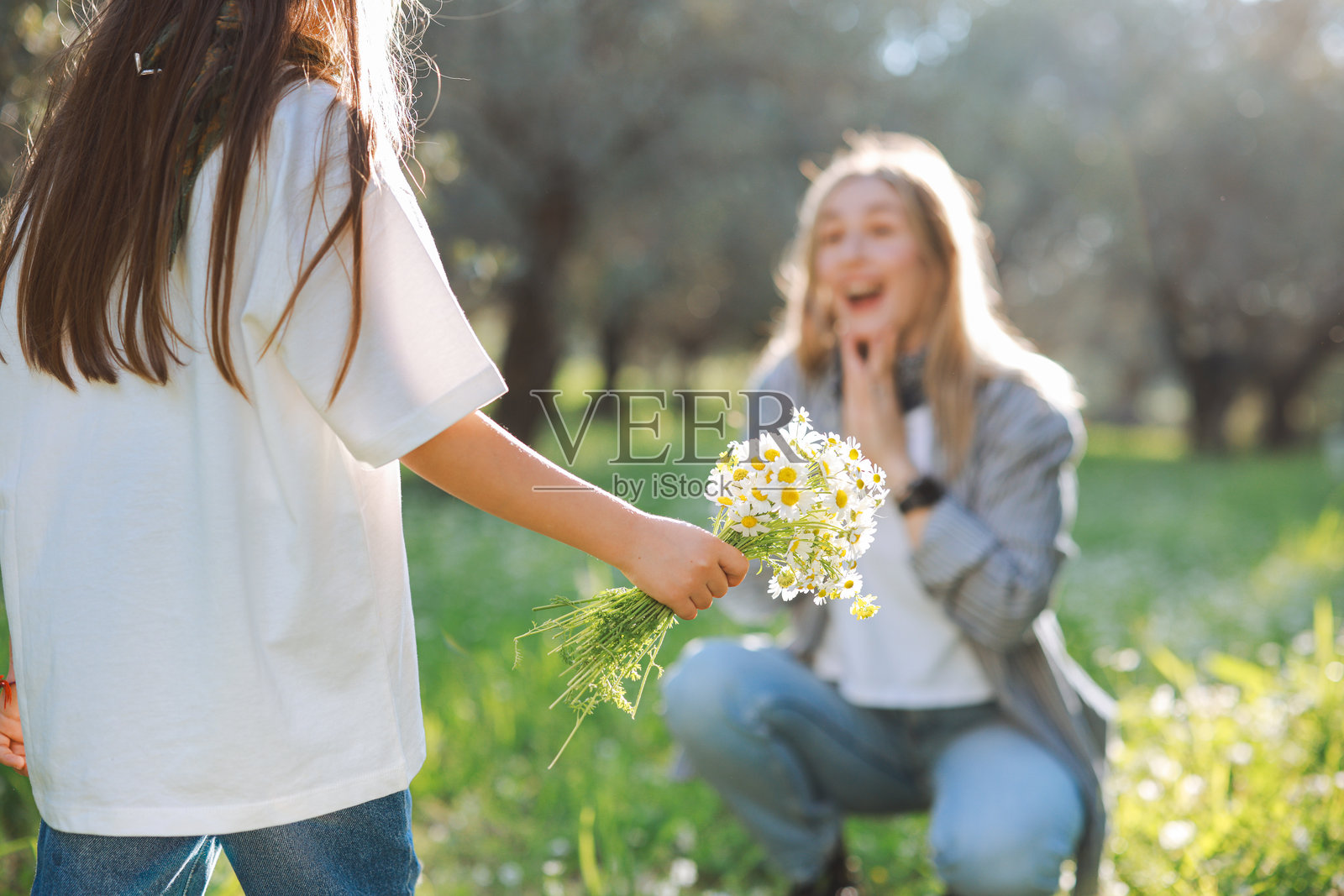 无忧无虑的年轻母亲和女儿在春天的日子里拥抱。照片摄影图片