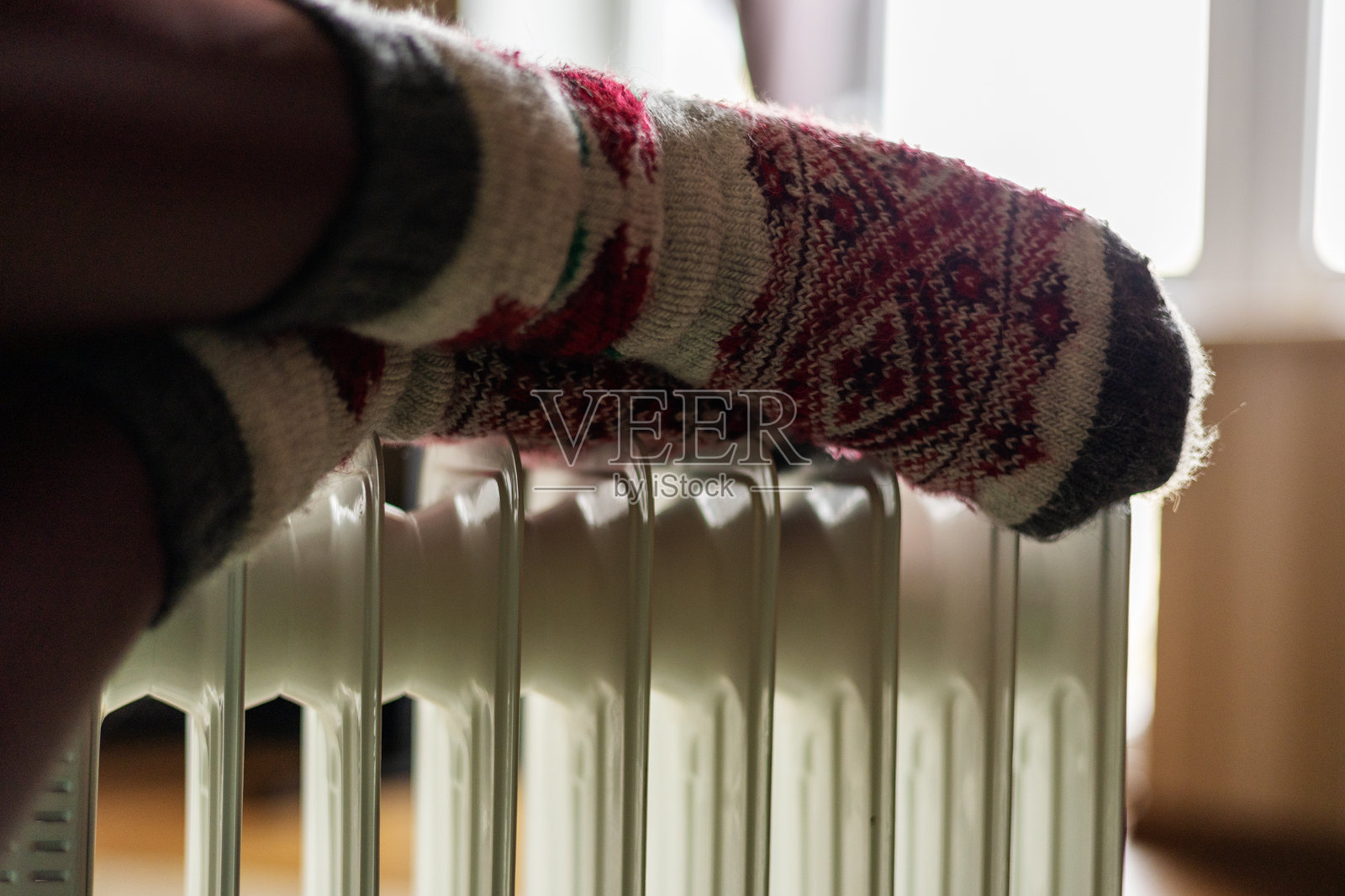 女人的腿穿着袜子，靠近暖气。照片摄影图片