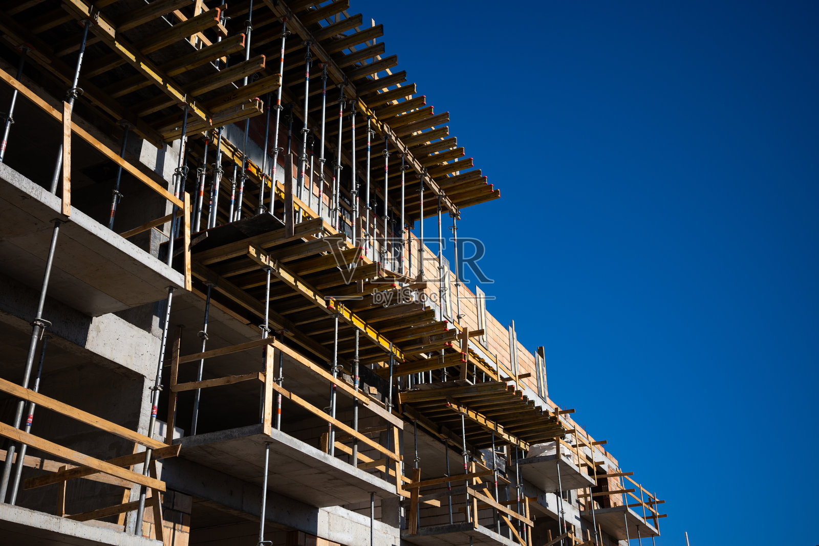 新建红砖公寓楼上的钢脚手架。照片摄影图片