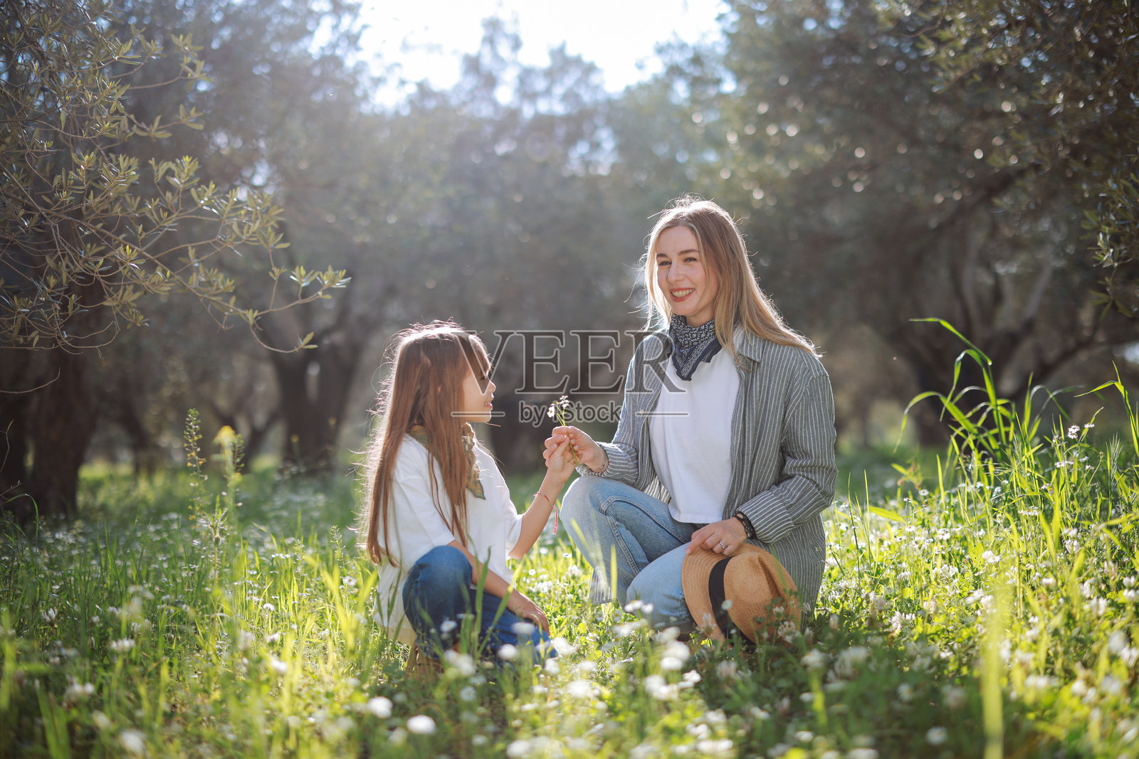 无忧无虑的年轻母亲和女儿在春天的日子里拥抱。照片摄影图片