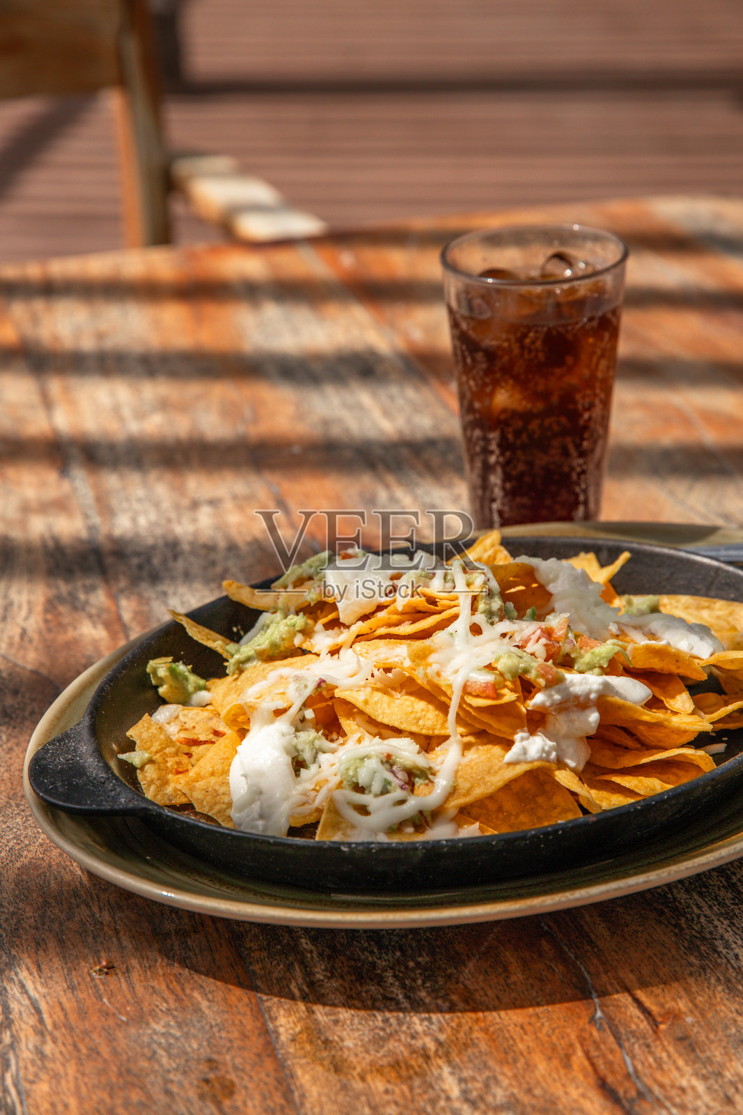 墨西哥奶酪玉米片配酸奶油、鳄梨酱和番茄，在图卢姆海滩边的餐厅里搭配冰可乐。照片摄影图片
