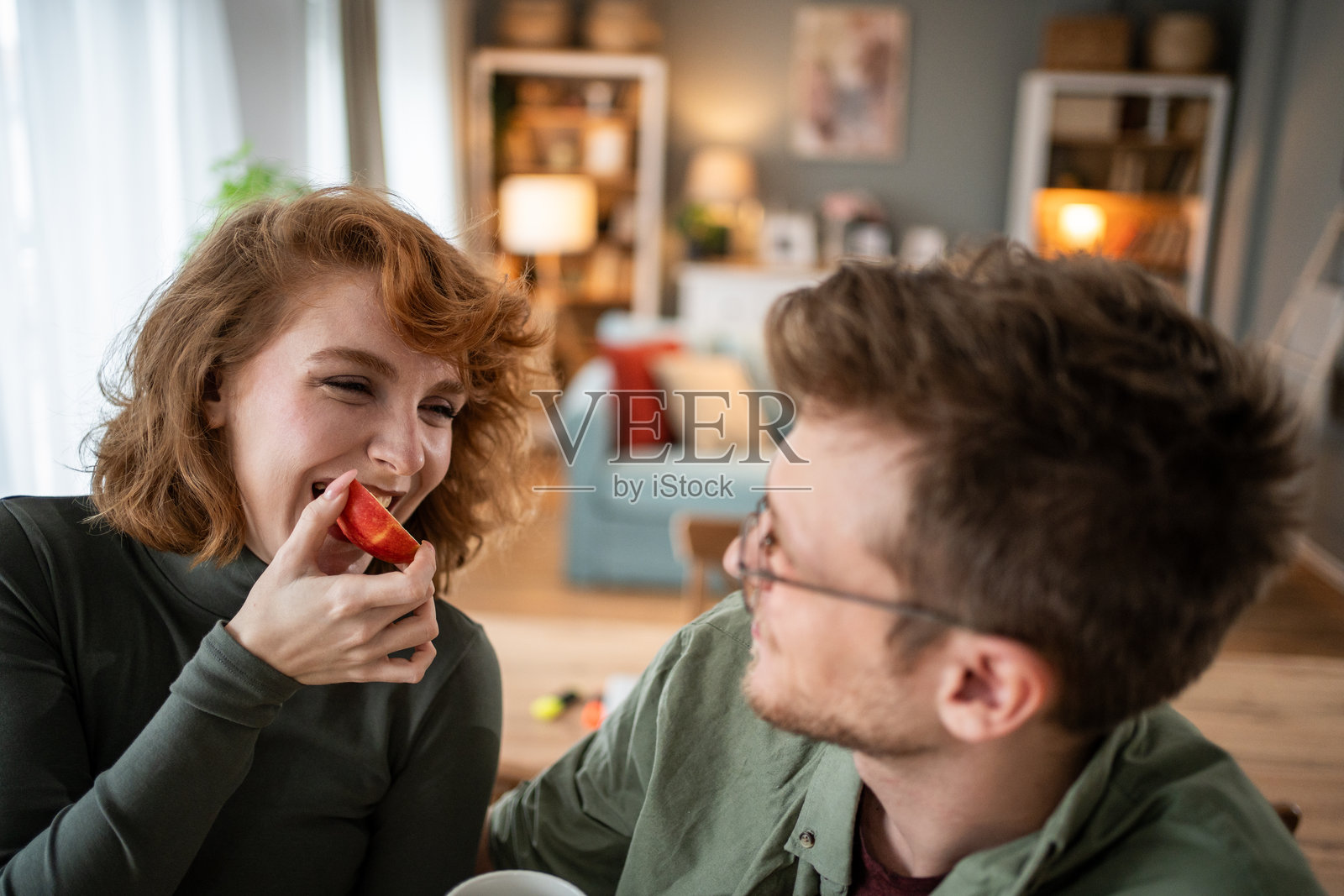 年轻情侣在家里轻松愉快地分享吃苹果的时刻照片摄影图片