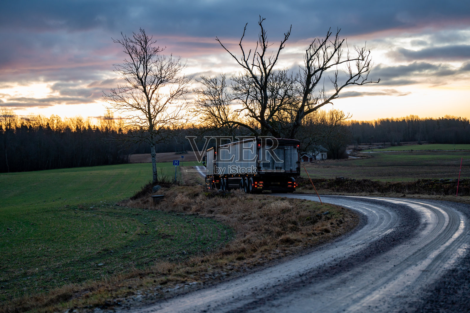 在狭窄潮湿且柔软的碎石路上行驶的卡车和拖车照片摄影图片