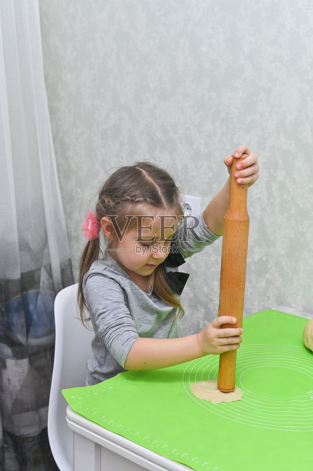 一个小女孩在厨房桌子上擀面团照片摄影图片