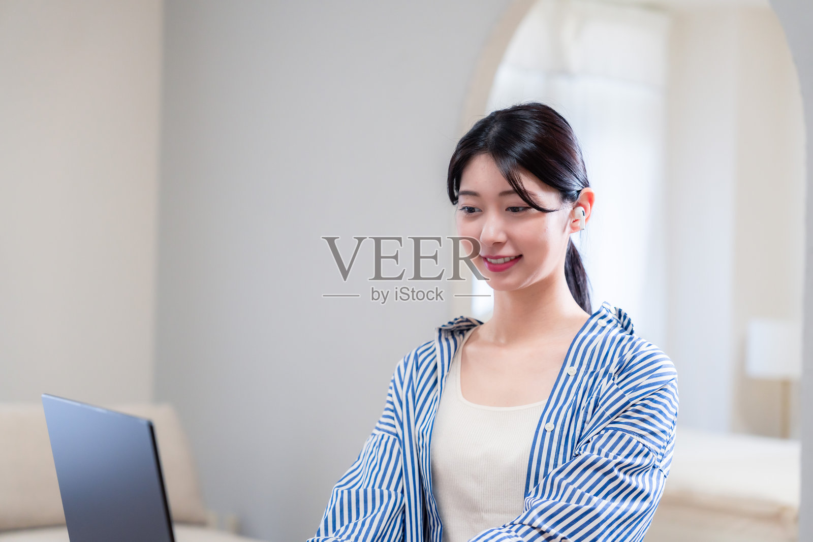 年轻女性在家参加远程会议，脸上挂着微笑照片摄影图片