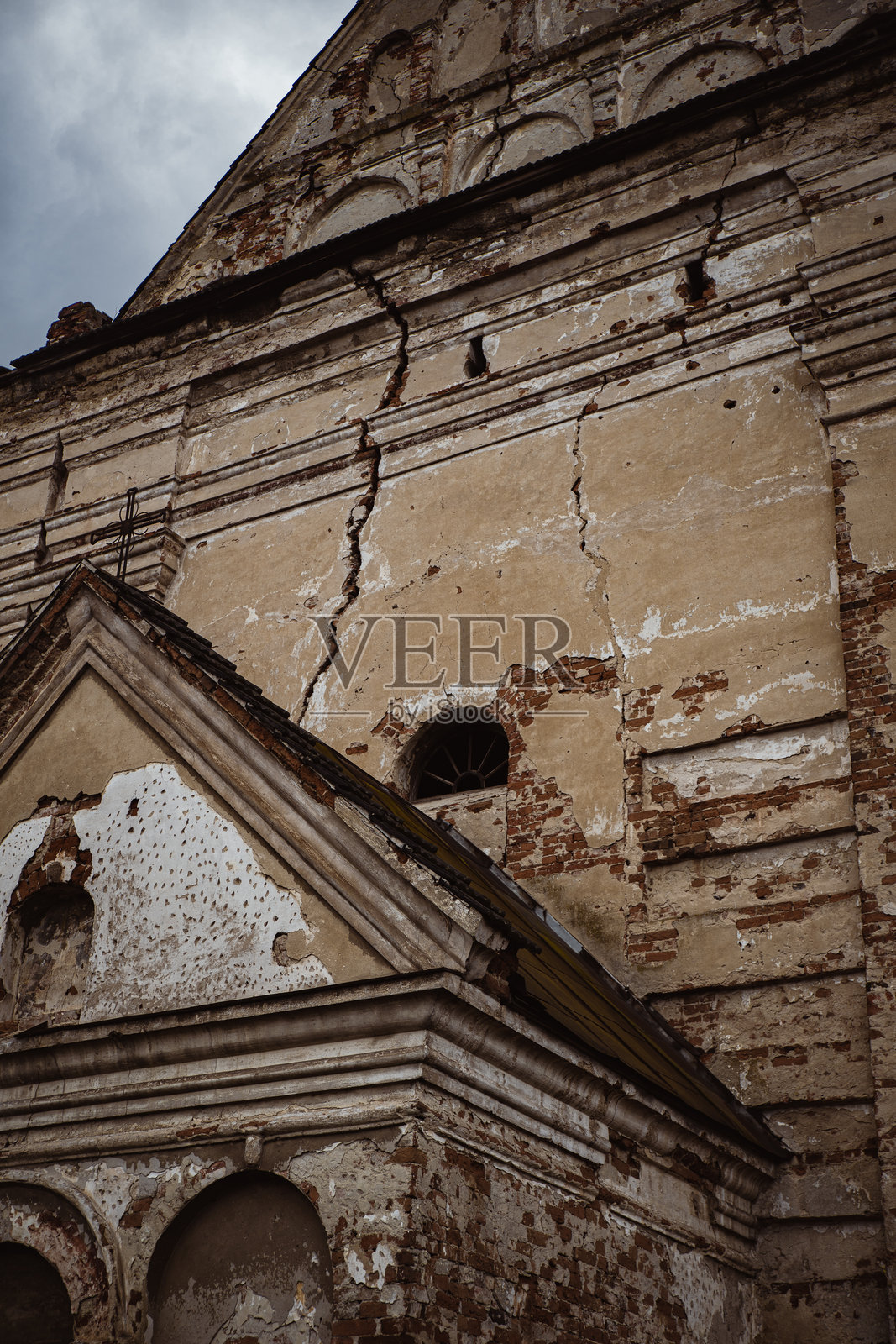 废弃地点下的破旧历史建筑，墙面开裂和剥落的油漆，阴云密布的天空。乌克兰雅沃里夫历史教堂照片摄影图片