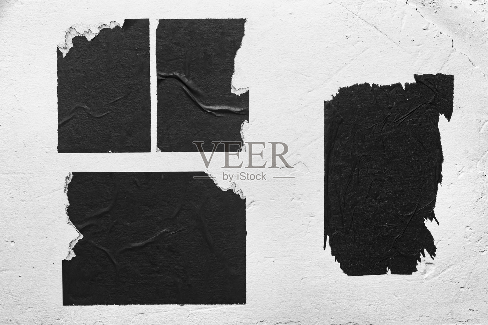 白墙上的黑色撕裂海报。照片摄影图片