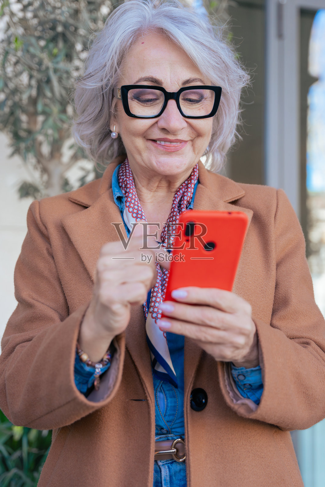 微笑的白人老年女性在城市环境中使用智能手机照片摄影图片