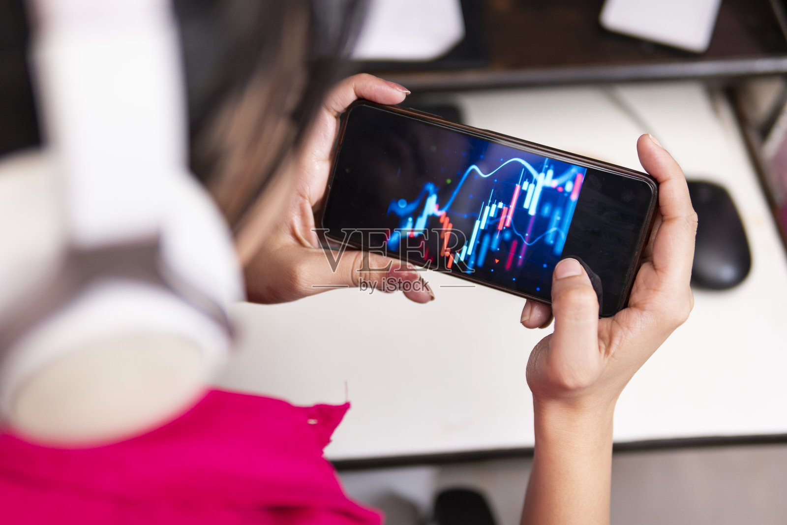 Z世代年轻女性在智能手机和电脑显示器上浏览投资交易数据。照片摄影图片