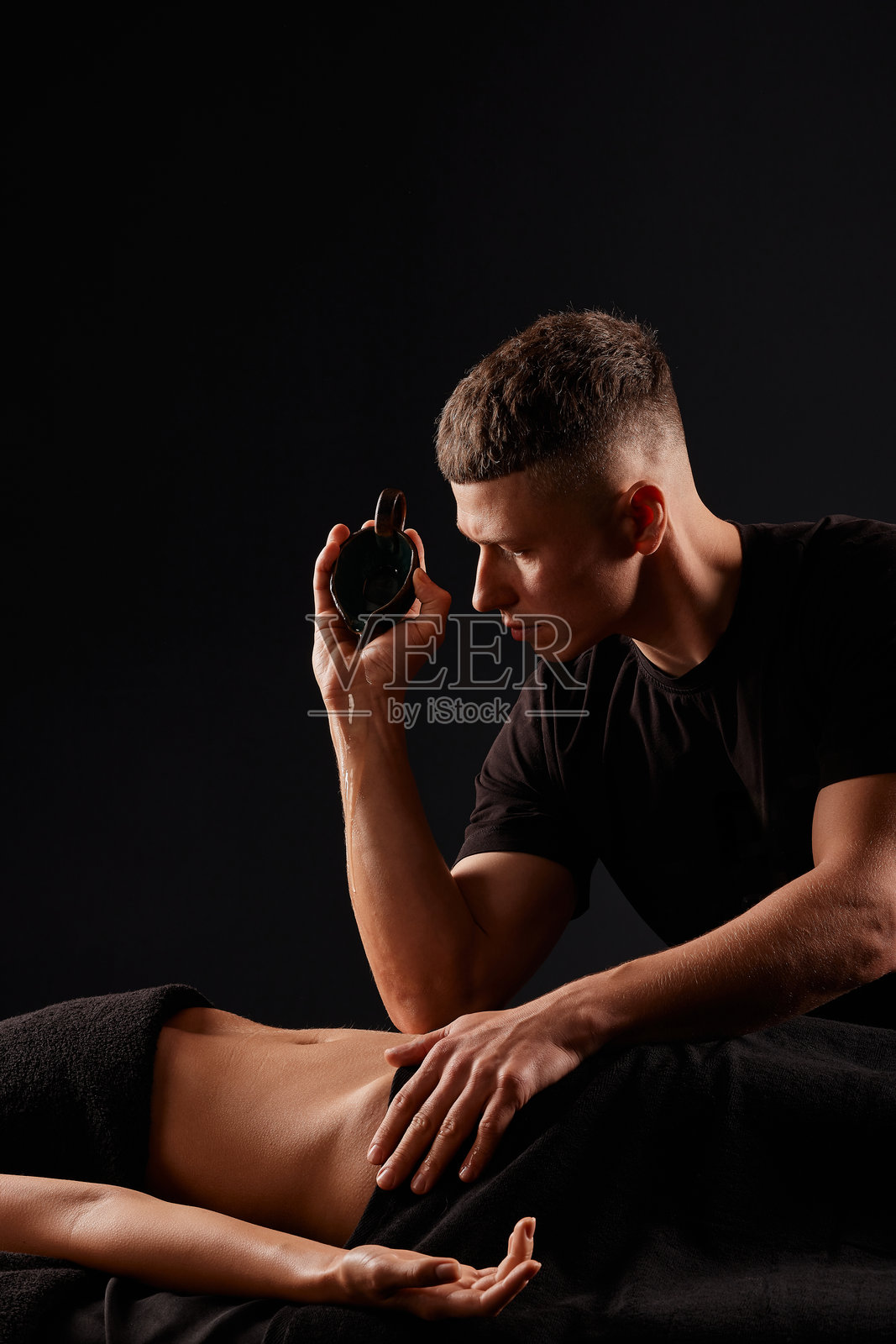 一名男性按摩师在黑暗背景下为女孩按摩颈部，颈部按摩照片摄影图片