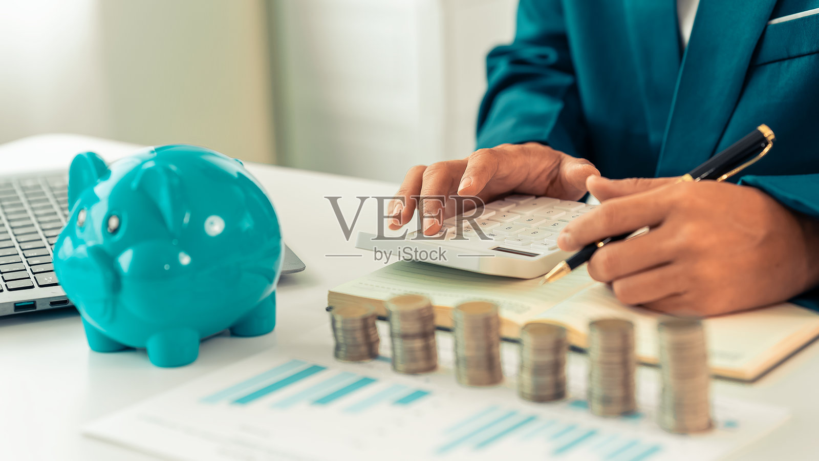 商人用计算器和存钱罐以及桌上的一堆硬币在工作。财务会计概念。照片摄影图片