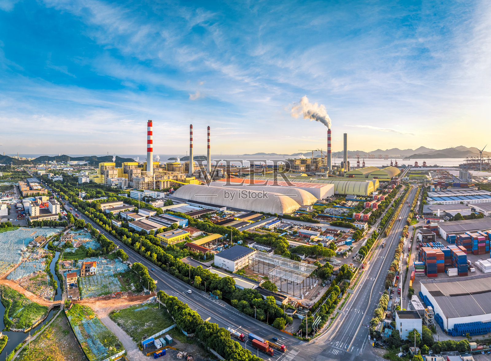 大型工业区的鸟瞰图，展示了一座工厂和一座发电厂，蓝天清澈。照片摄影图片