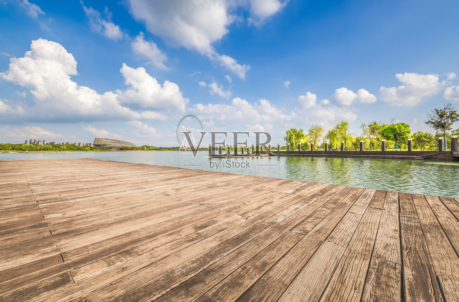 风景如画的木栈道提供了迷人的湖景，背景是晴朗的蓝天和摩天轮。照片摄影图片