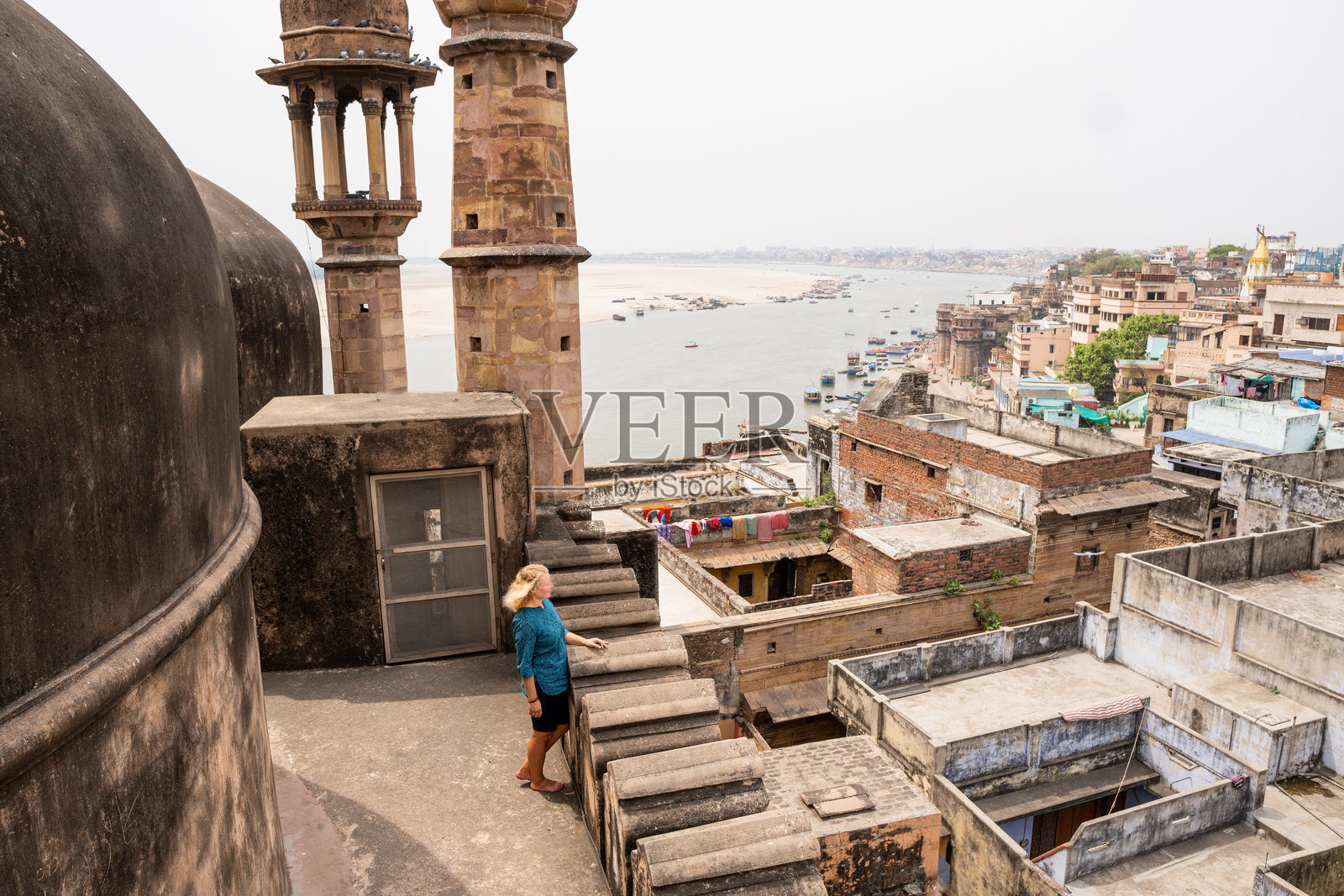 年轻女性站在印度北方邦瓦拉纳西老城的清真寺屋顶上，俯瞰恒河。照片摄影图片
