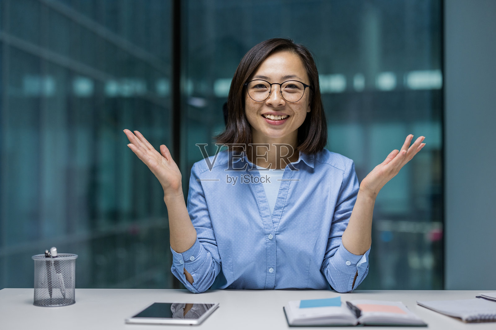 网络摄像头视角，快乐的亚洲女性微笑着看向镜头，满足地与同事和合作伙伴通过视频通话交流，进行在线会议。照片摄影图片